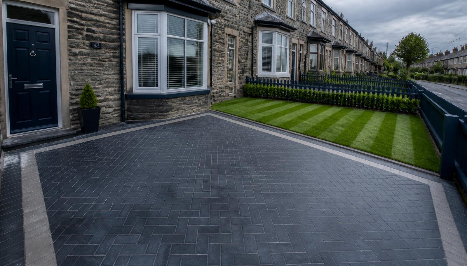 A newly laid paved driveway beside a freshly cut lawn
